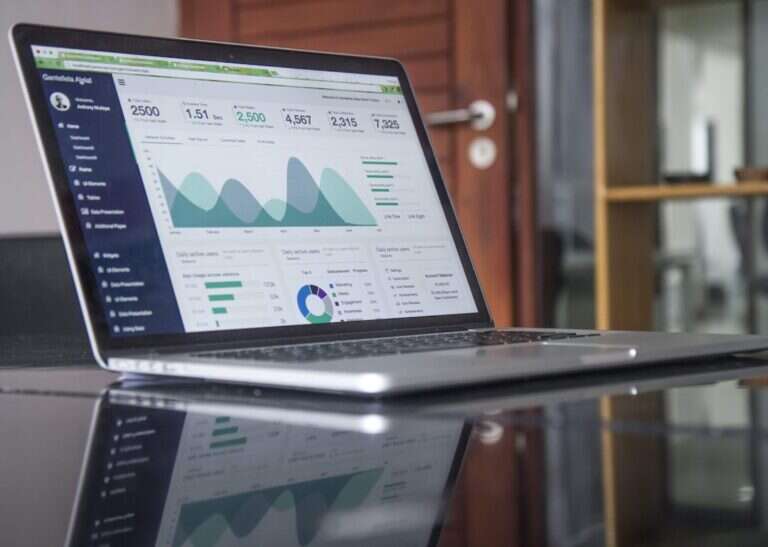 Laptop on a glass table showing a revenue analytics dashboard