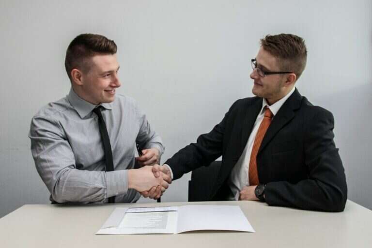 Hiring manager and new hire shaking hands over a signed offer