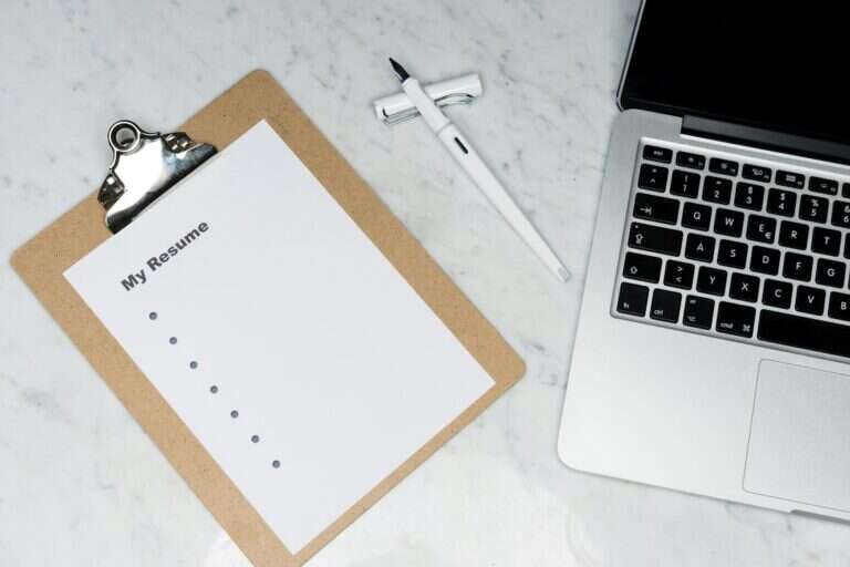 Candidate CV on a clipboard beside a laptop