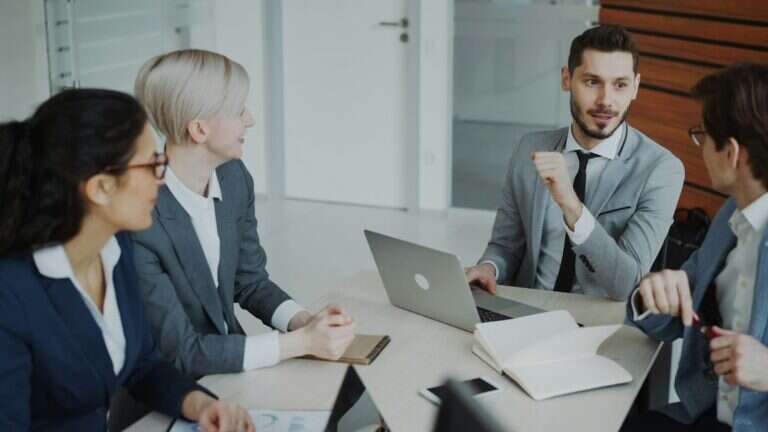 Go-to-market team discussing numbers around a laptop