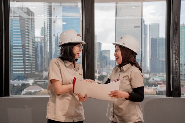 Two engineers in hard hats reviewing construction drawings on site