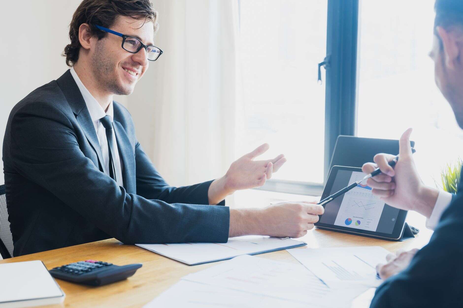 Account executive walking a client through charts on a tablet at a desk