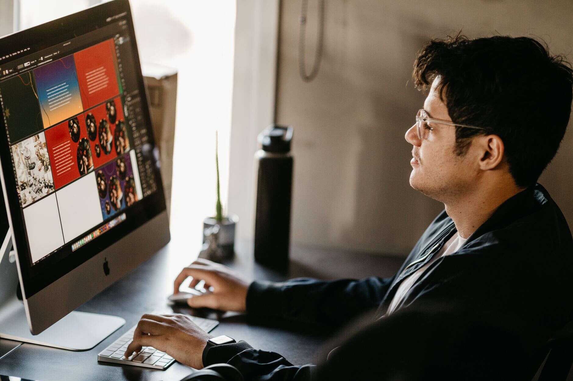 Graphic designer working on brand layouts at a desktop computer