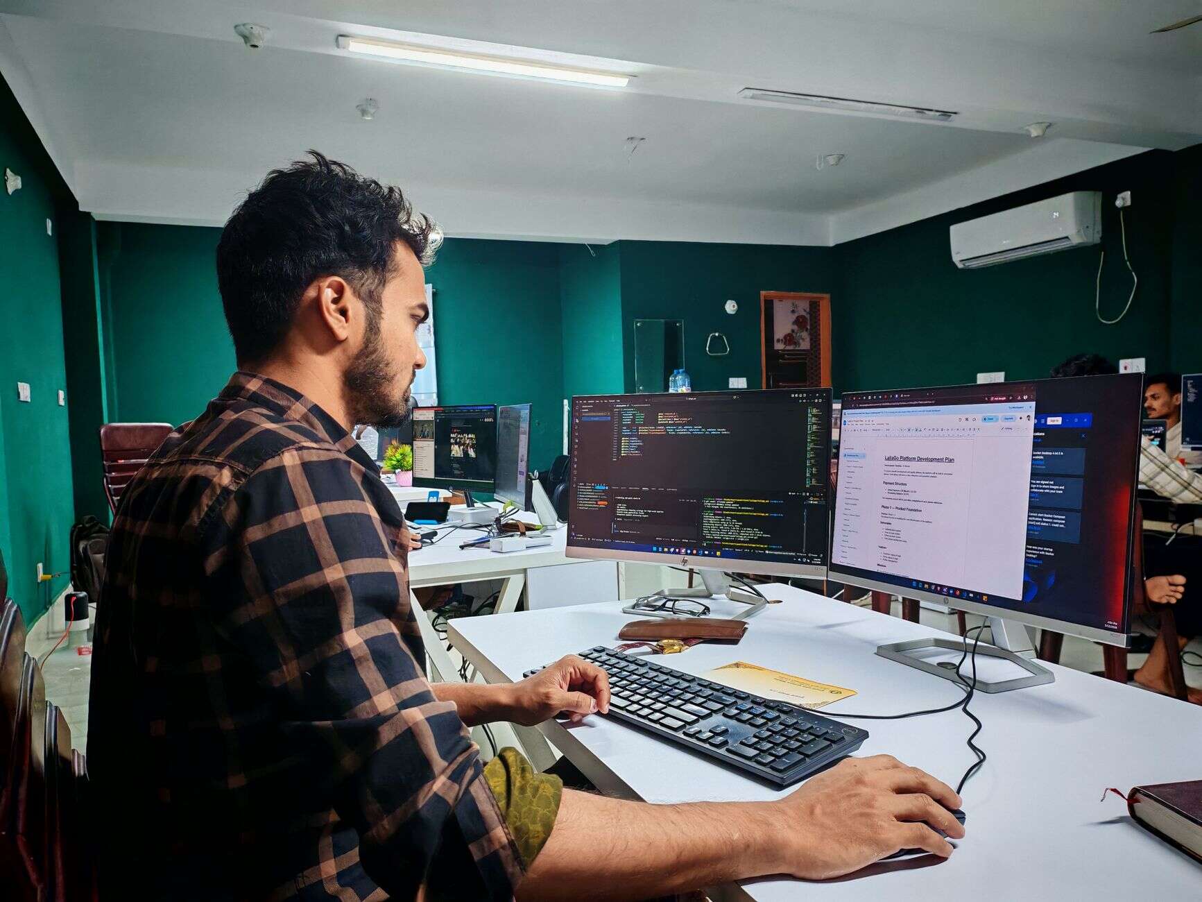 WordPress developer working on site code across two monitors in an office