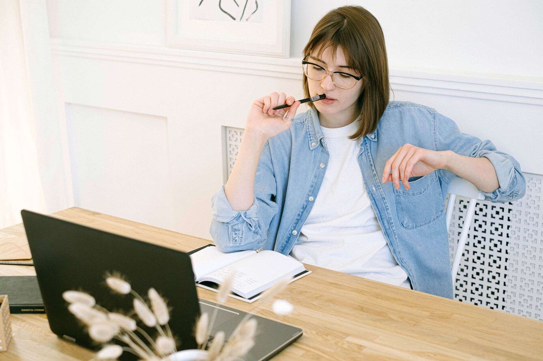 Content writer thinking through a draft beside her laptop and notebook