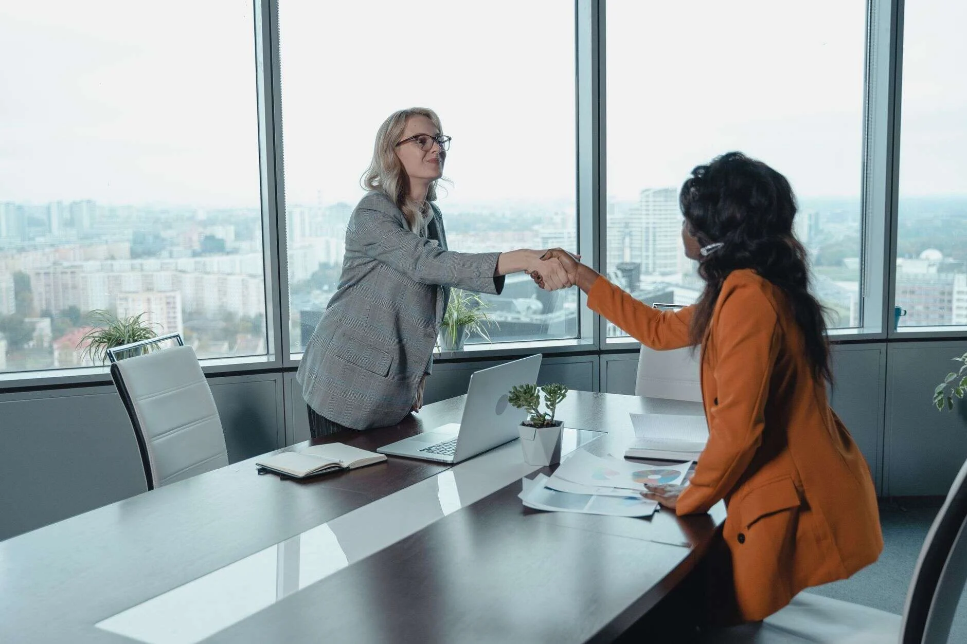 Two partners shaking hands at a meeting in a high-rise office