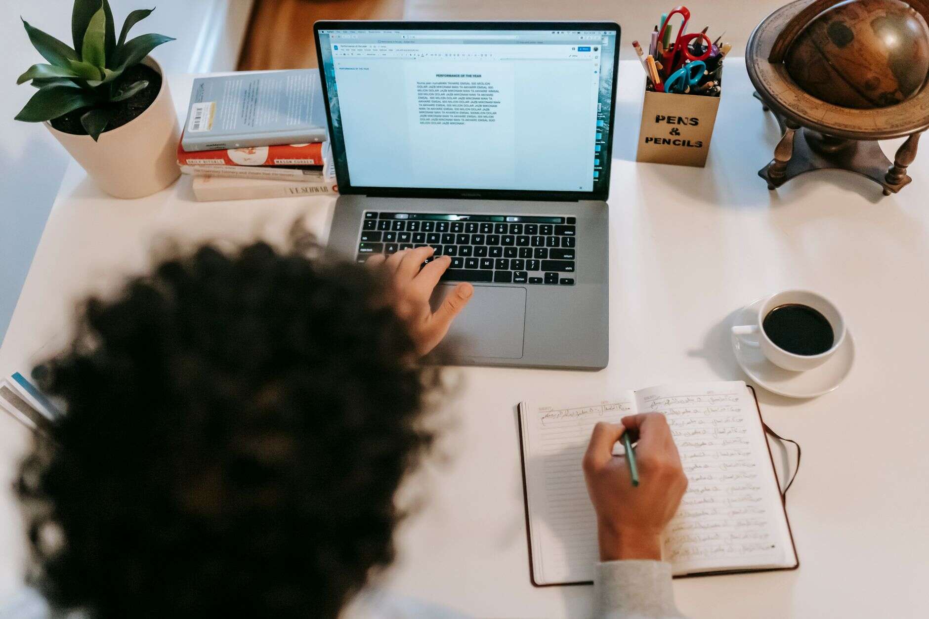Content writer drafting an article on a laptop beside handwritten notes