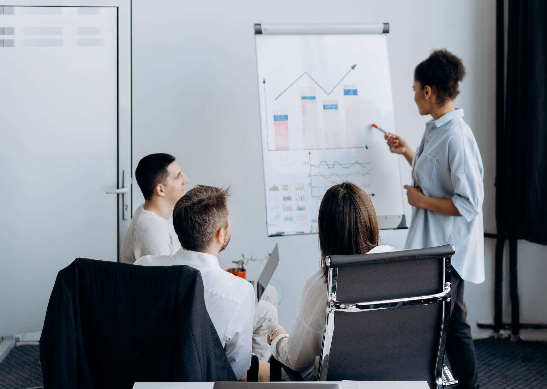 Sales manager walking the team through pipeline charts on a flip board