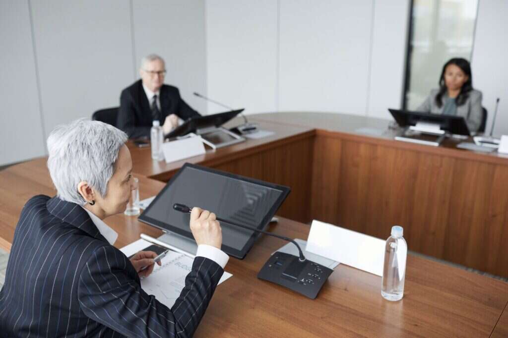 Directors at a boardroom table reviewing a tablet during a meeting