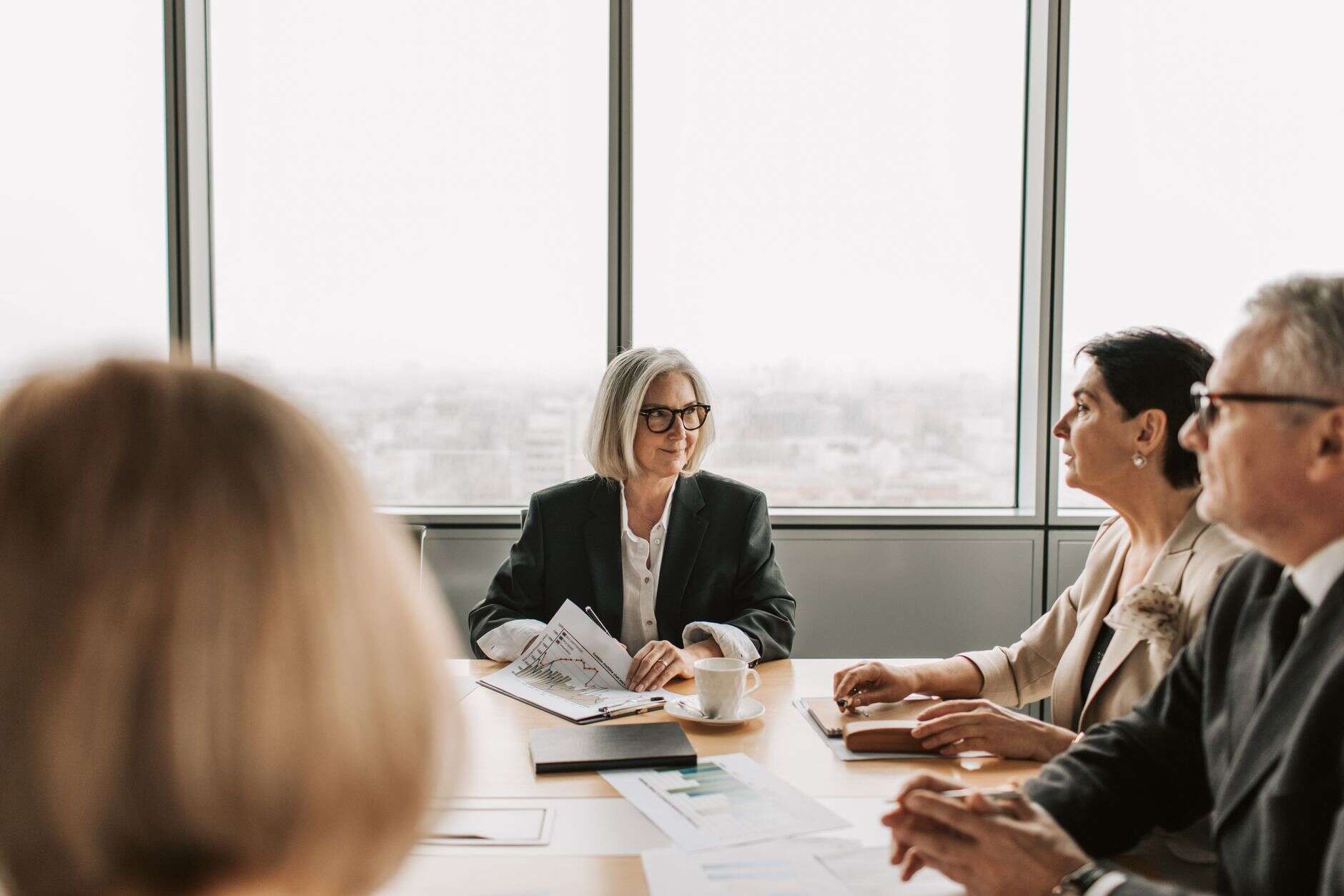 Senior leadership team in a board meeting reviewing papers