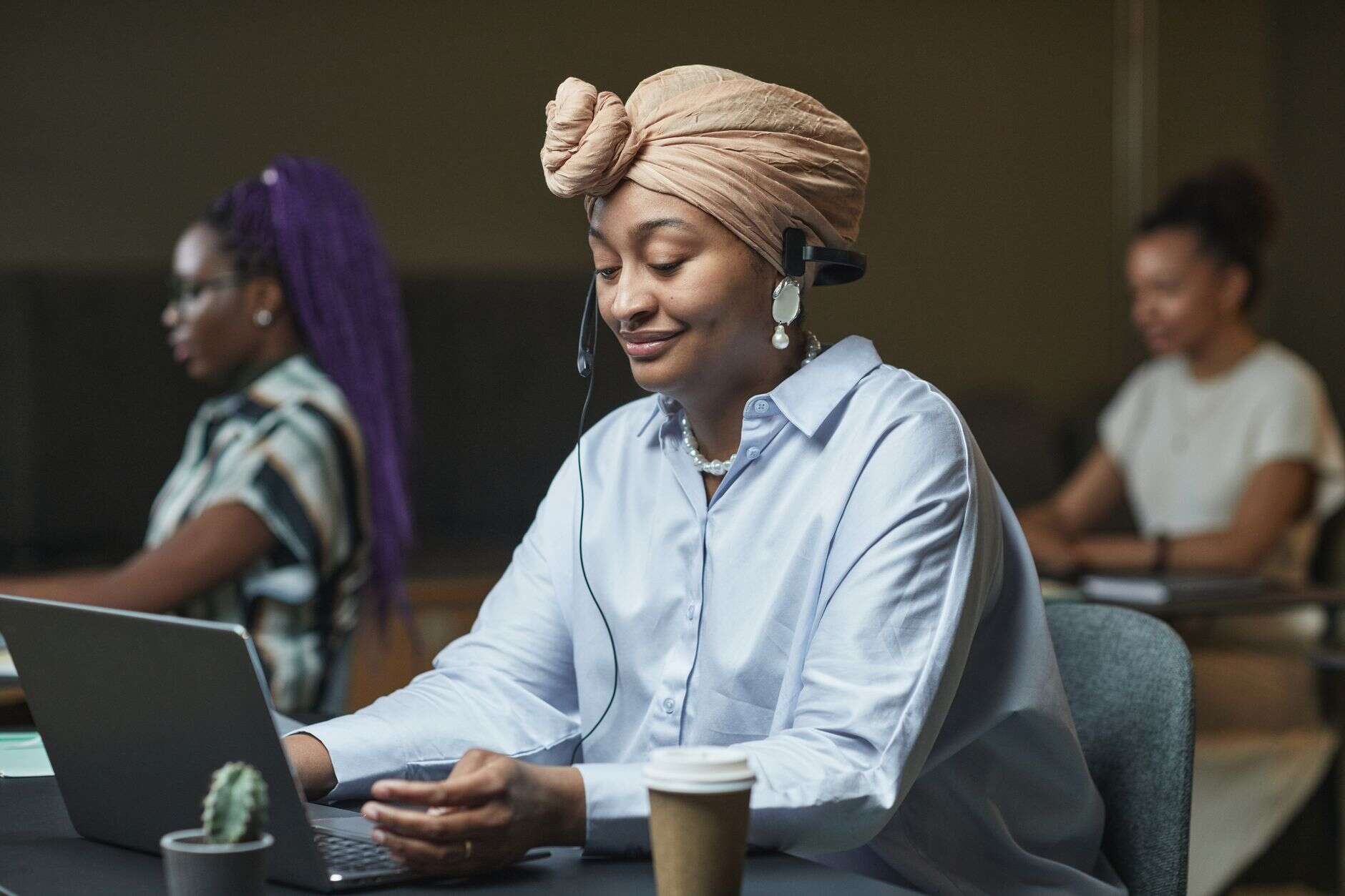 SDR on a headset working through calls at her laptop in a shared office