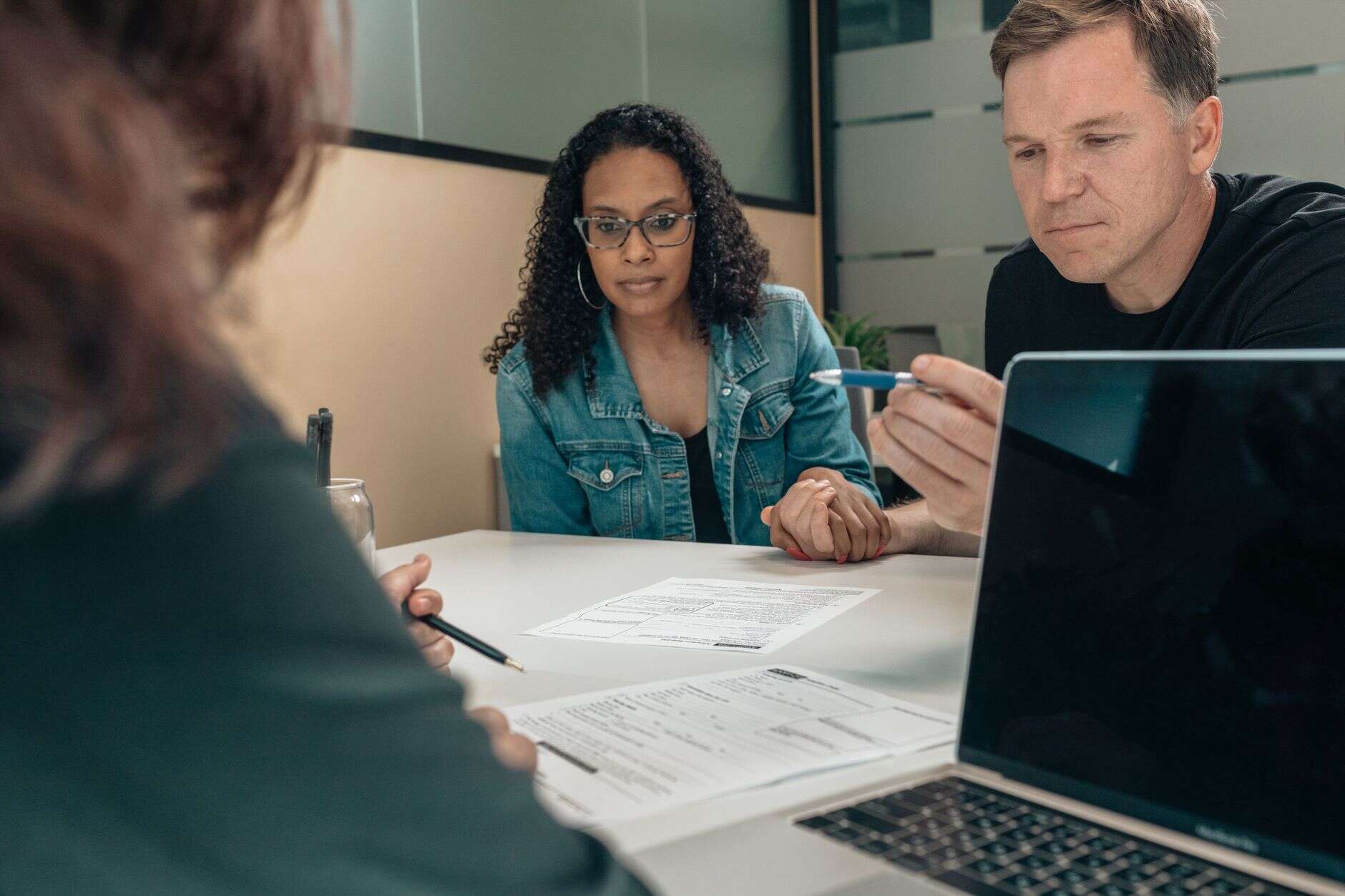 Account manager walking two clients through documents at a meeting table