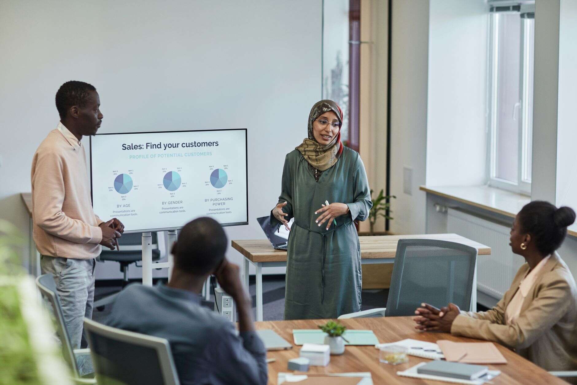 Sales leader presenting customer profile charts to a team at a meeting table