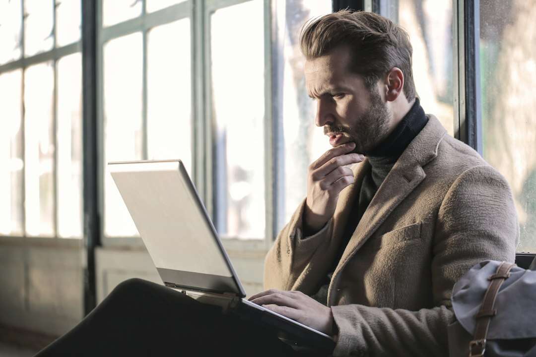 Communications manager drafting a statement on a laptop and pausing to think