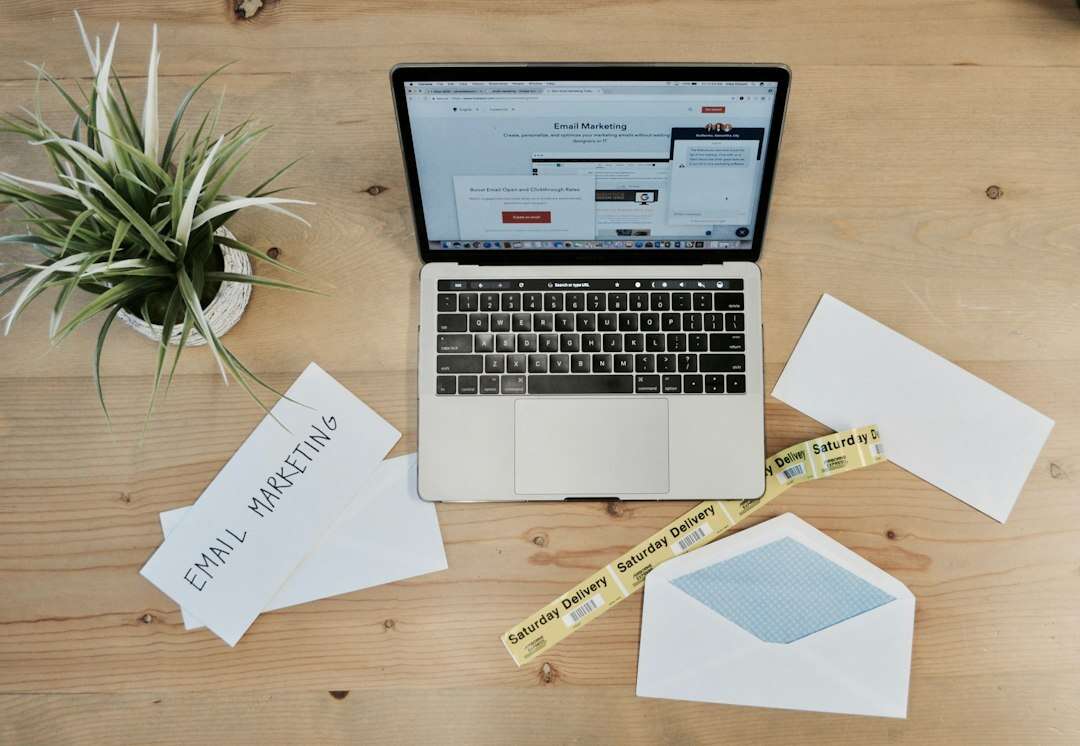 Laptop beside printed email marketing notes and envelopes