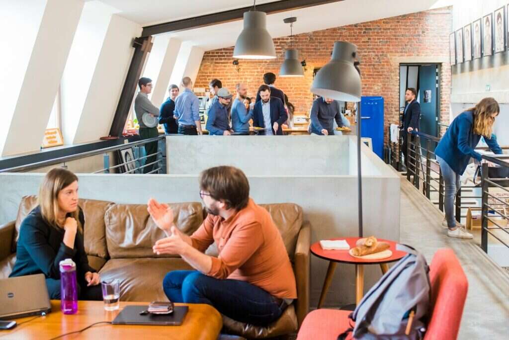 Colleagues talking on a lounge sofa in a loft-style tech office