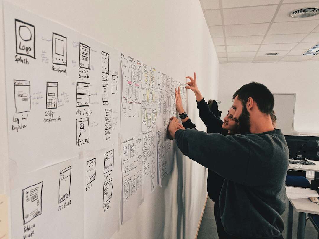 Two colleagues pinning hand-drawn page wireframes to a wall to plan landing page tests