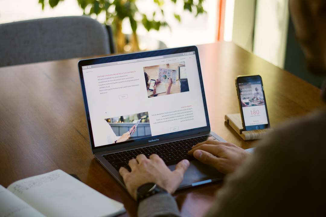 Website manager editing a site page on a laptop with a phone preview beside it