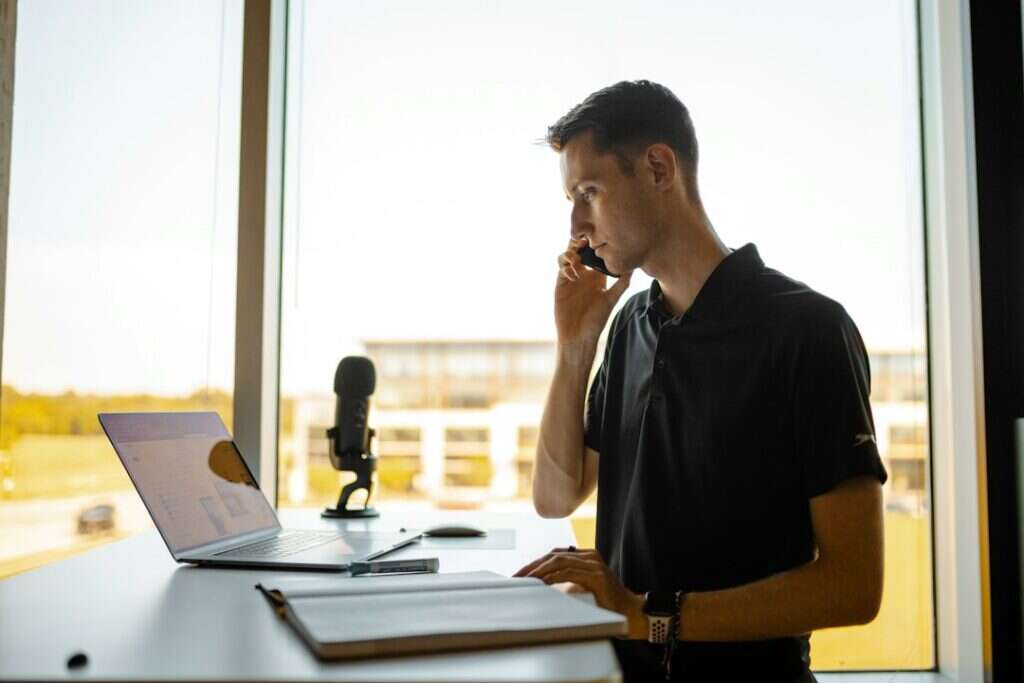 A recruiter on a phone call standing beside a bright office window