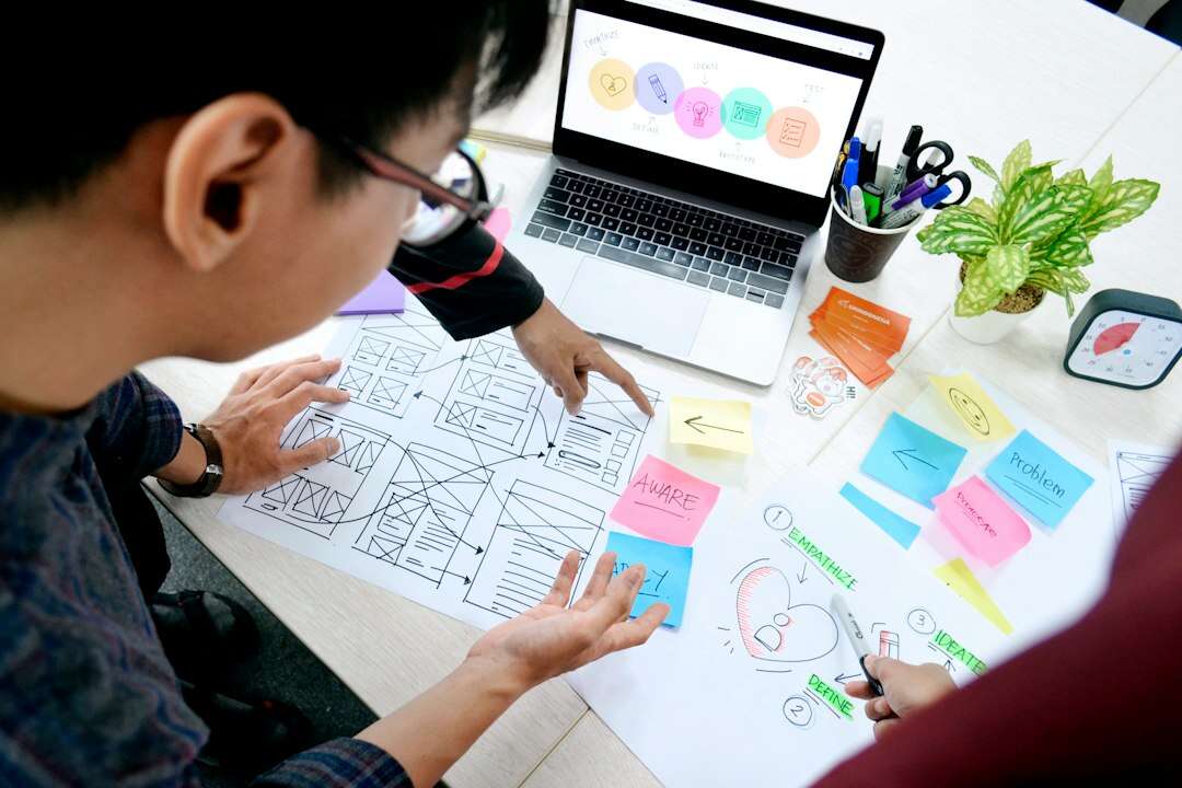 UX designer laying out wireframes and a journey map beside a laptop
