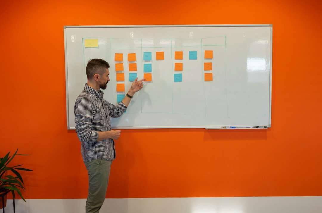 Content strategist pointing to sticky notes on a whiteboard planning grid