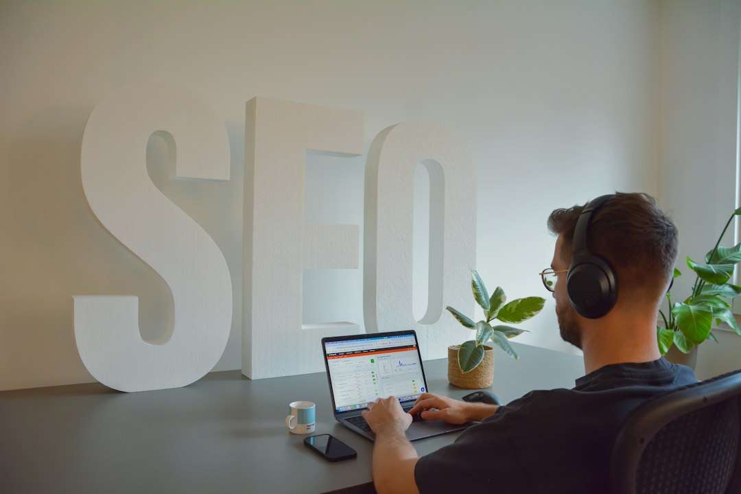 SEO strategist reviewing search performance on a laptop beside large letters spelling SEO