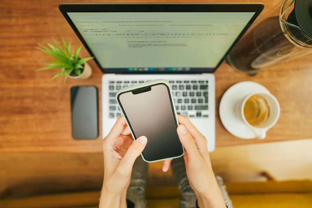 Front-end developer testing a site on a phone held above a laptop