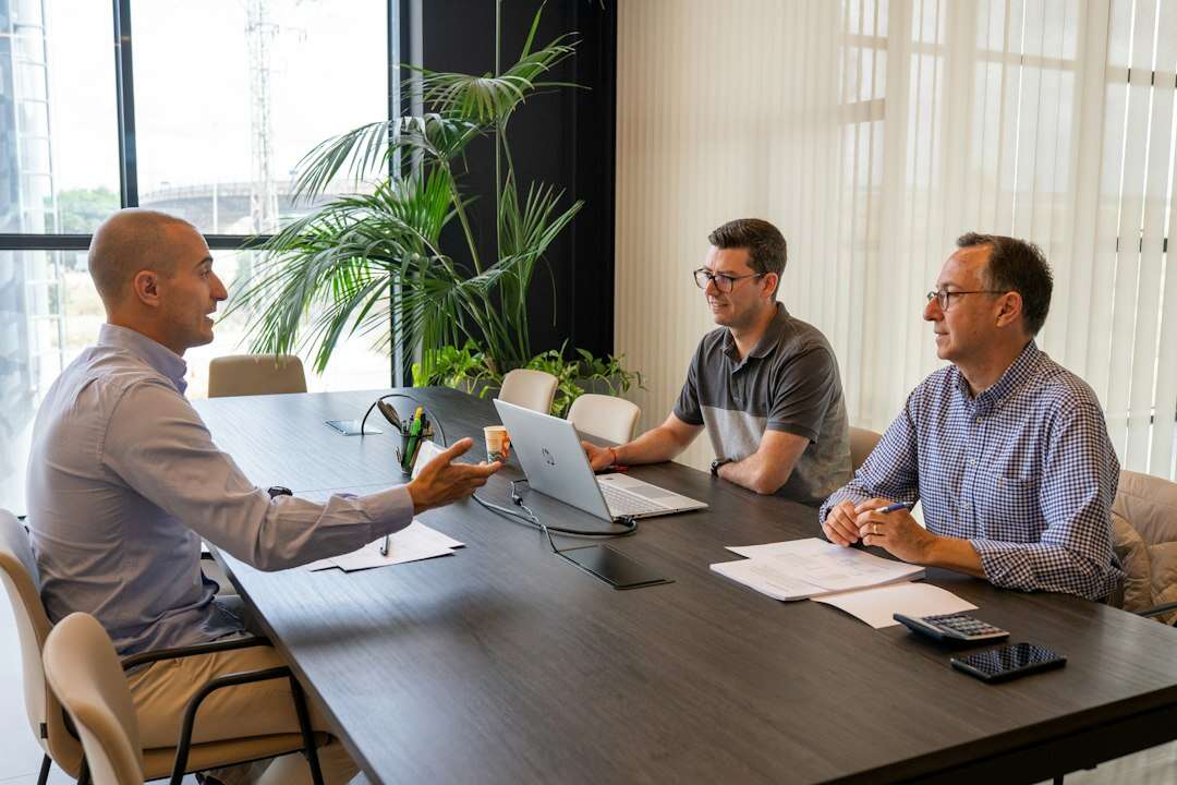 Commercial leader talking through terms with two colleagues across a conference table